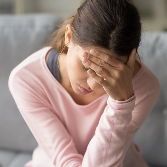 Eine Frau hält sich eine Hand vor die Stirn